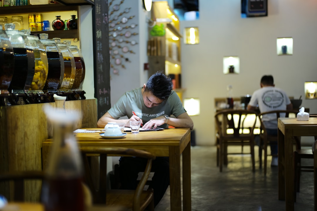 Man writing at a table in a dimly lit cafe